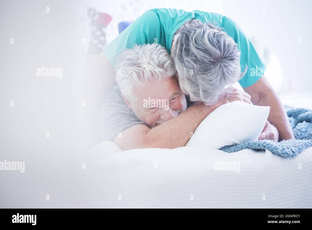 Ältere Paare spielen und haben Spaß auf dem Bett. Ältere Paare genießen miteinander. Sorglos altes Paar mit grauen Haaren Spaß verbringen Freizeit t Stockfoto
