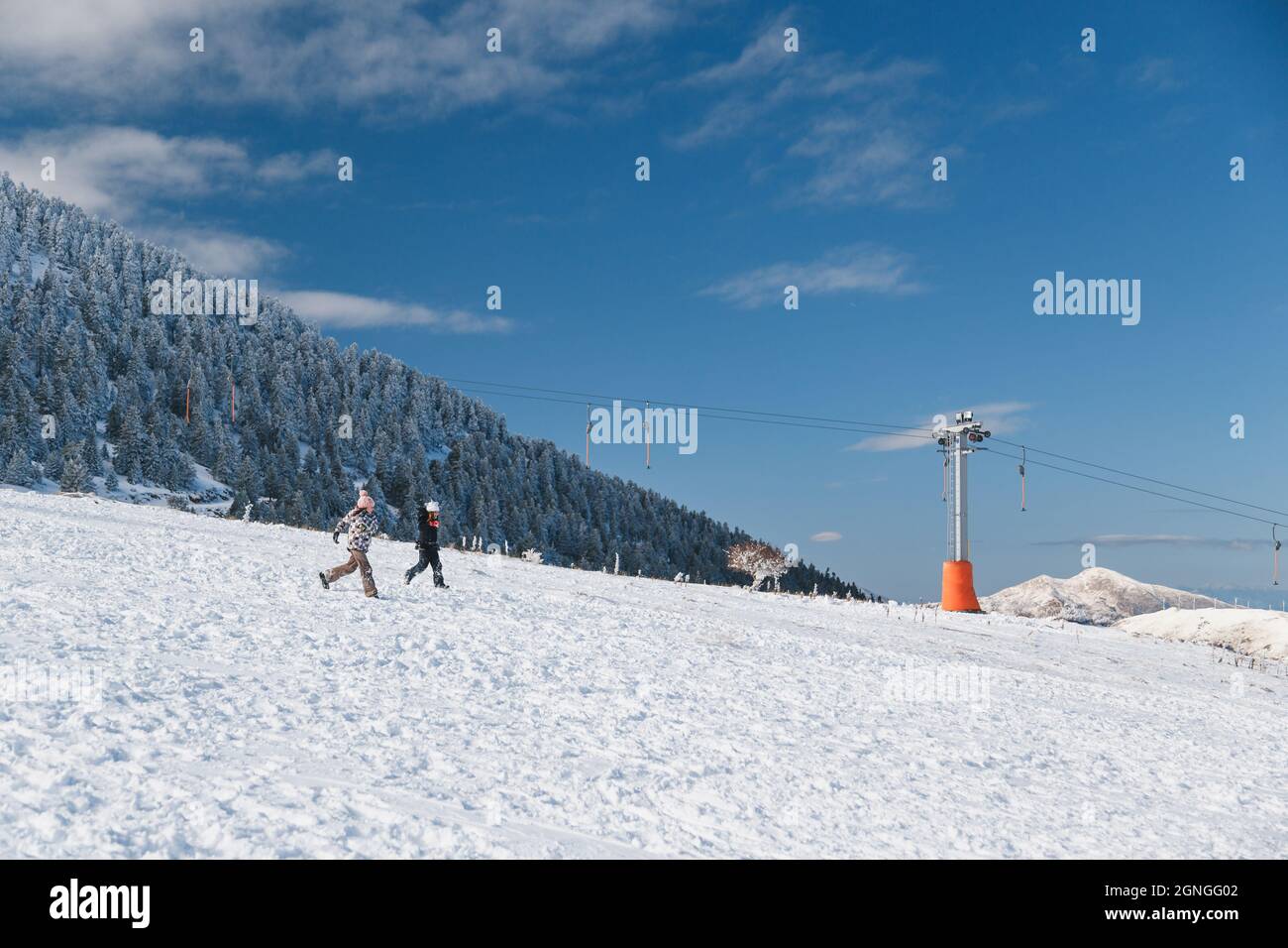 Kalavrita Ski Resort, Griechenland - Dezember, 31 2019: Zwei glückliche Mädchen, die in einer verschneiten Piste herunterlaufen und Winterferien im Skigebiet in Griechenland genießen. Kinder h Stockfoto