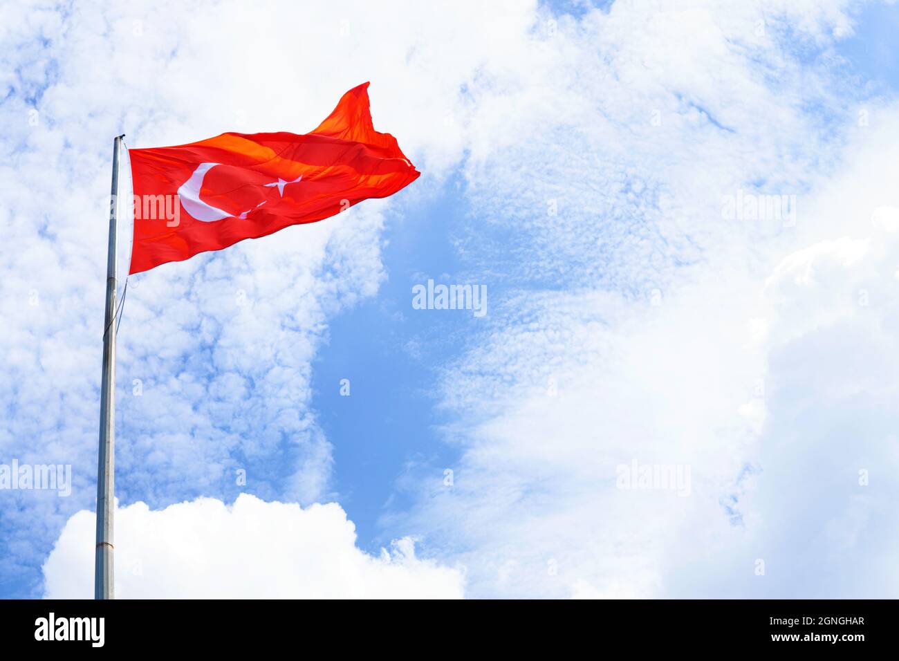 Blick auf die Flagge der Türkei, die an einem sonnigen Tag gegen den blauen Himmel schwenkt Stockfoto