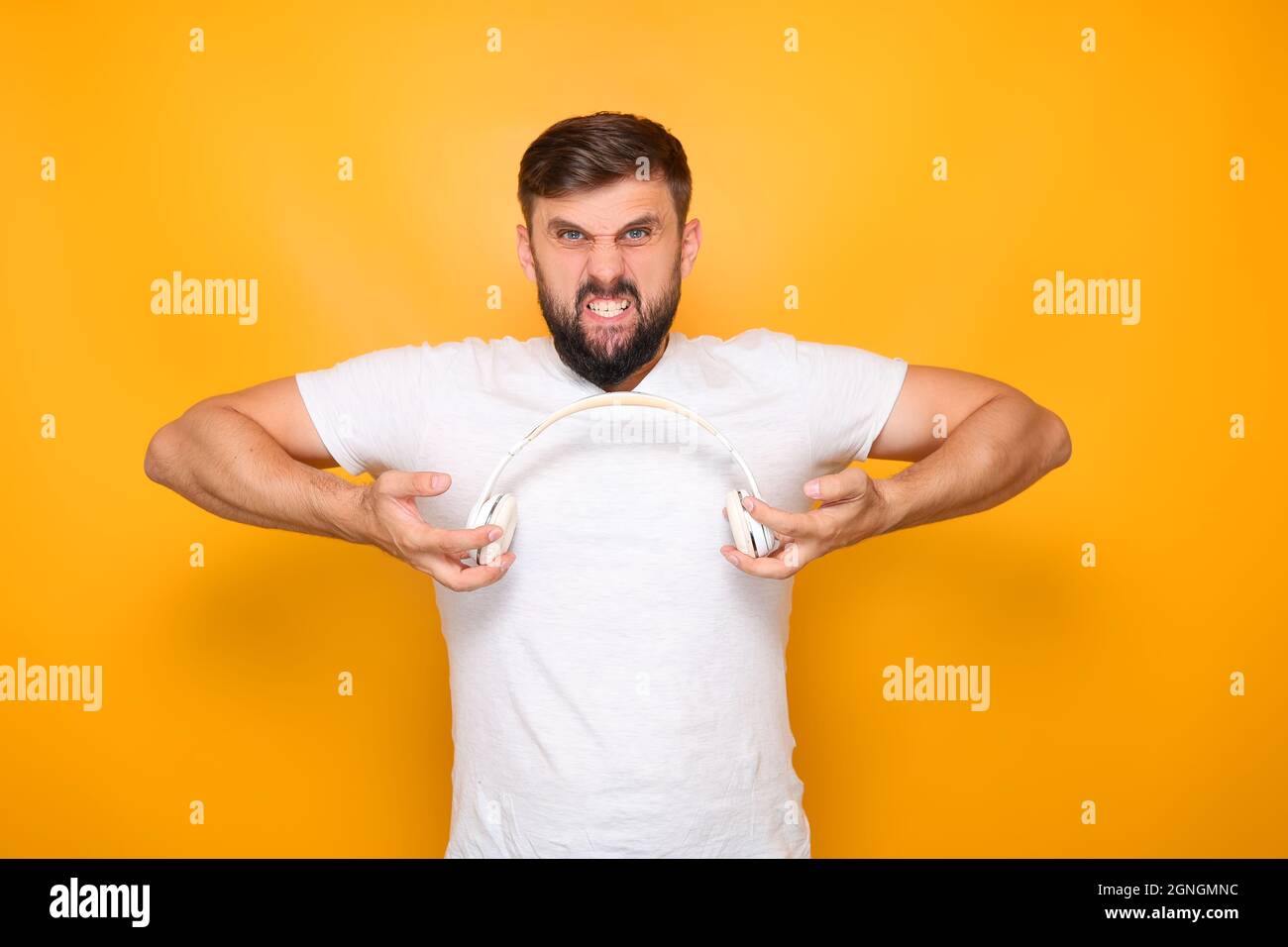 Bärtiger Mann, Musikliebhaber hält weiße Kopfhörer vor sich. Stockfoto