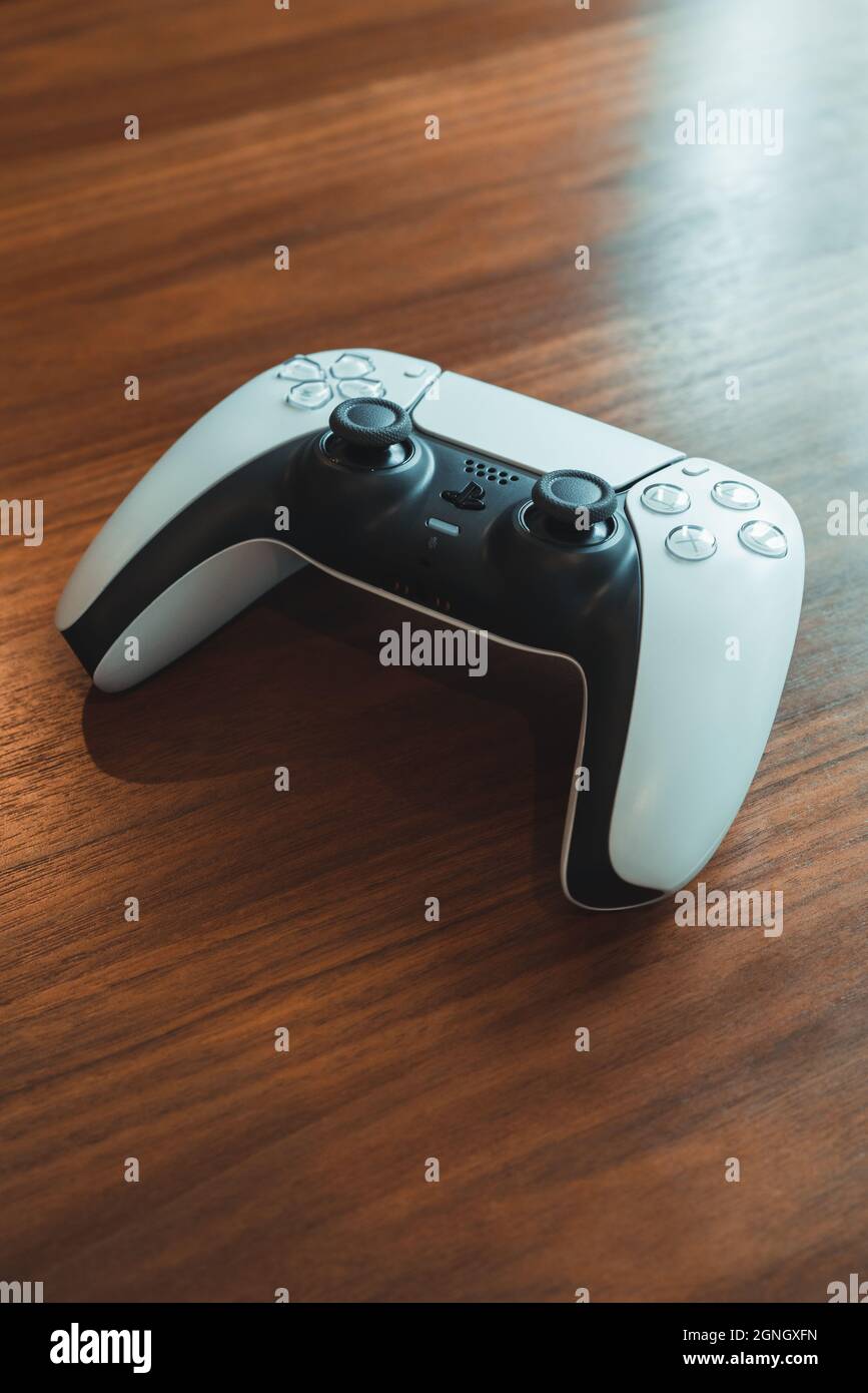 London, Großbritannien - 25. Mai 2021: Weißer, kabelloser PlayStation 5 (PS5)-Controller auf einem Holztisch, selektiver Fokus. PlayStation 5 ist das neueste Videospiel CO Stockfoto