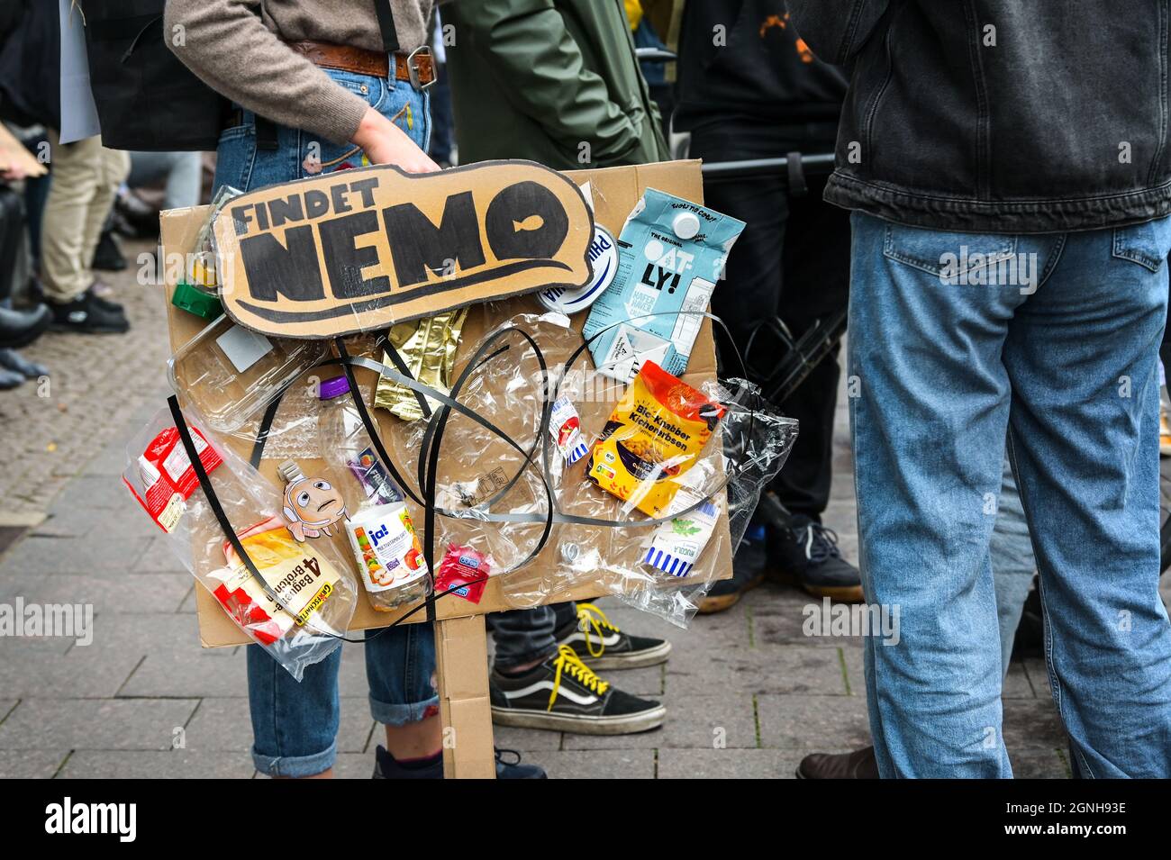 Lübeck, 24. September 2021: Junge Studentin hält ein kreatives Protestschild aus Pappe, das mit viel Plastikmüll und Texterfassung verklebt ist Stockfoto