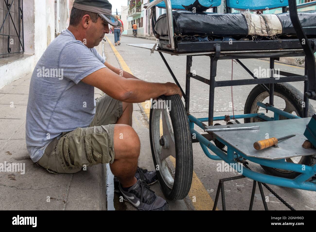 Mann repariert einen Platten Reifen in Bicitaxi, Camaguey, Kuba, 2016 Stockfoto