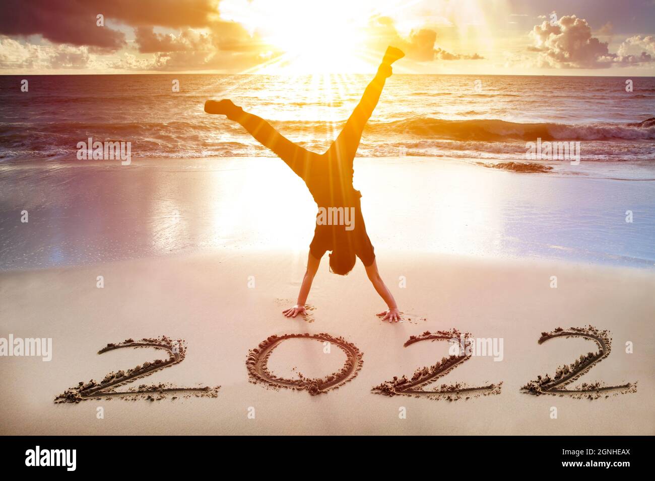 Junger Mann Handstand am Strand. Glückliches neues Jahr 2022 Konzept Stockfoto