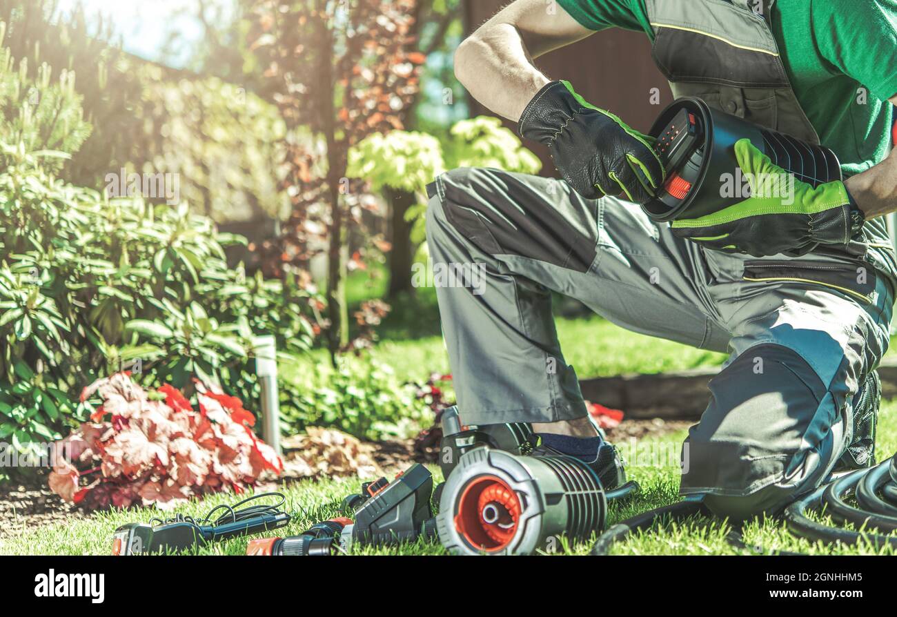 Automatische Backyard Garten Bewässerung System Installation durchgeführt von professionellen kaukasischen Garten Techniker. Automatische Rasensprinkler Stockfoto