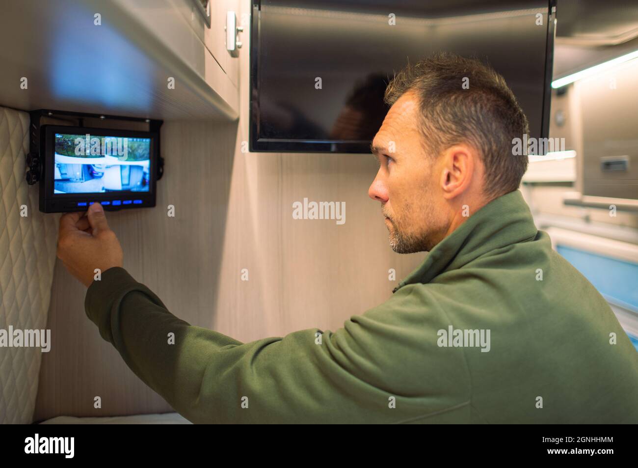 CCTV-System im Wohnmobil mit Außenansicht des Wohnmobils. Kaukasische Männer Fertigstellung Der Installation. Vierfach-Videoansicht. Modernes Caravaning-Design. Stockfoto