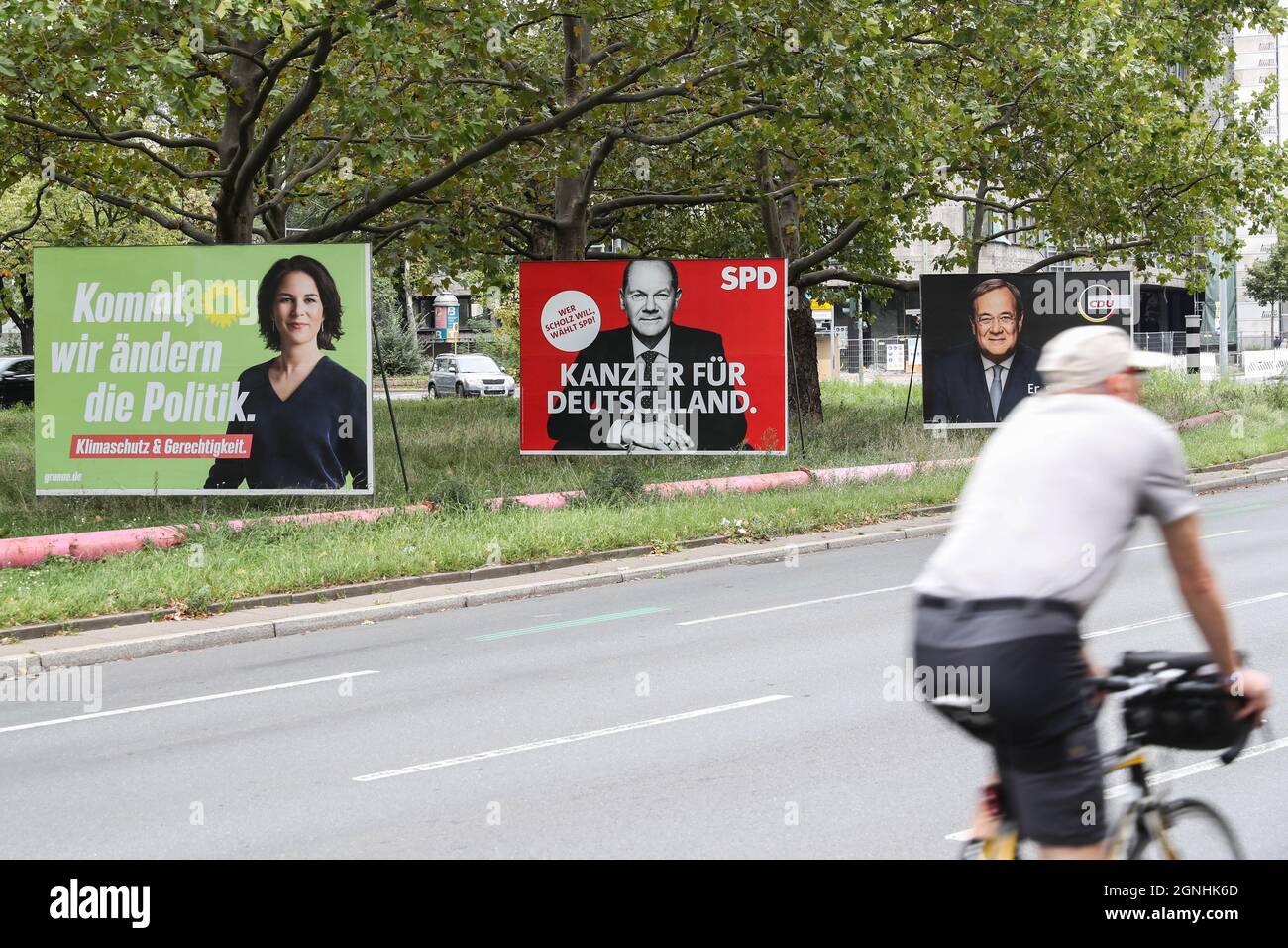 Berlin, Deutschland. September 2021. Ein Radfahrer fährt am 25. September 2021 in Berlin an den Wahlplakaten der Kanzlerkandidaten (von L bis R) Annalena Baerbock von den Grünen, Olaf Scholz von der SPD und Armin Laschet von der CDU/CSU vorbei. Die Deutschen wählen am Sonntag die Mitglieder des 20. Bundestages des Landes. Insgesamt werden 6,211 Kandidaten aus 47 politischen Parteien um mindestens 598 Sitze konkurrieren. Kredit: Shan Yuqi/Xinhua/Alamy Live Nachrichten Stockfoto