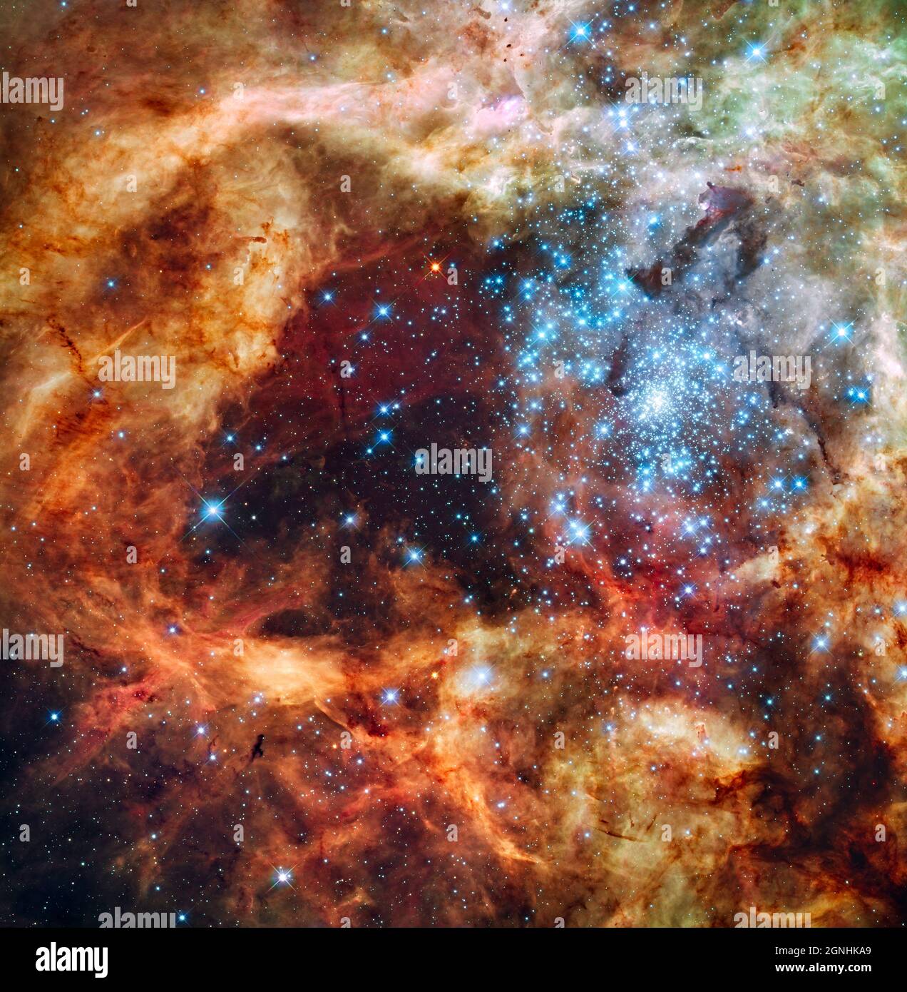 Die massive, junge Sterngruppe, genannt R136, ist erst wenige Millionen Jahre alt und findet sich im Doradus-Nebel von 30, einer turbulenten Sternentstehungsregion in der Großen Magellanischen Wolke (LMC).viele der diamantartigen eisblauen Sterne gehören zu den massereichsten bekannten Sternen. Einige von ihnen sind über 100 Mal massereicher als unsere Sonne. Das Bild ist etwa 100 Lichtjahre lang. Die brillanten Sterne schnitzen tiefe Hohlräume im umgebenden Material, indem sie einen Strom ultravioletten Lichts freisetzen und Sternwinde mit Hurrikankraft, die die umhüllenden Wasserstoffwolken wegreißen Stockfoto
