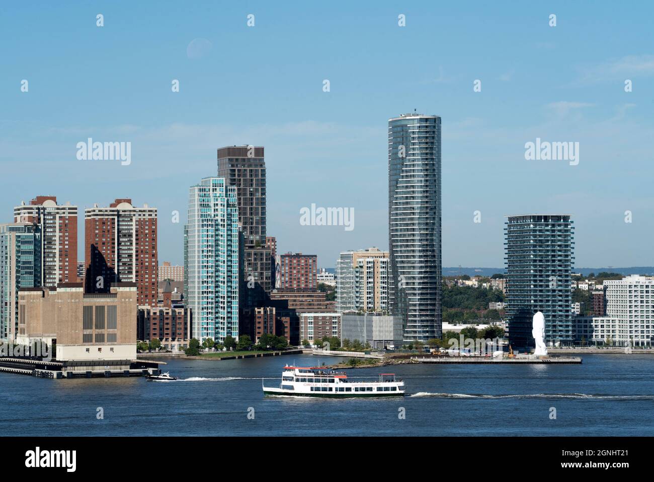 Ein Ausflugsboot der Circle Line, das den Hudson River entlang an Jersey City, New Jersey, und eine 80 Meter hohe Skulptur am Wasser von Jaume Plensa führt. Stockfoto