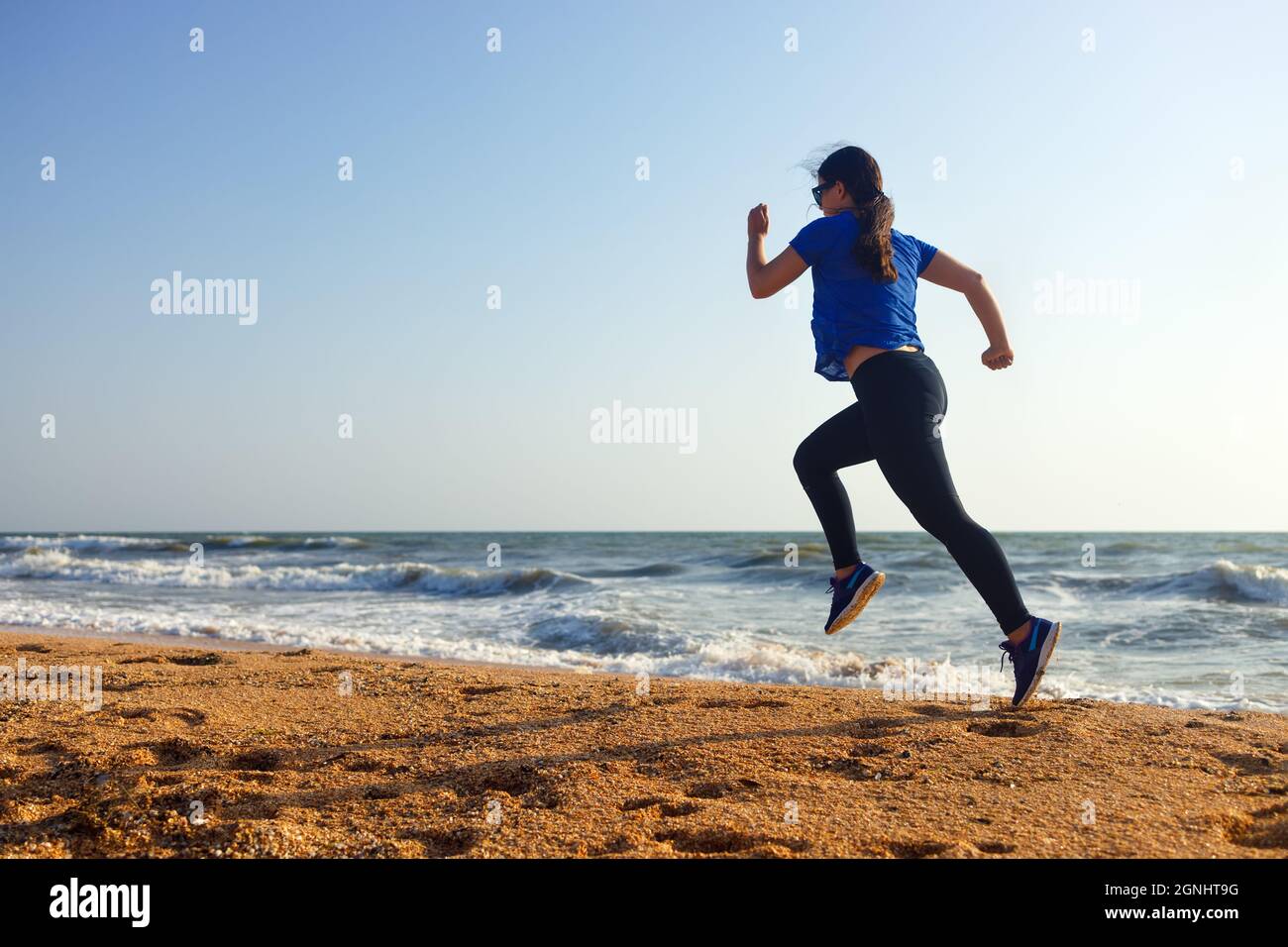 Frau, die morgens am Strand am Meer herumläuft Stockfoto