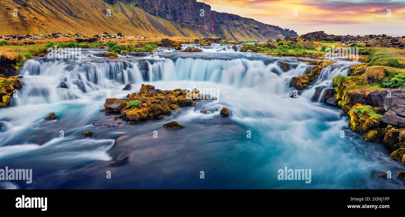 Panoramablick auf den kleinen Wasserfall in der Nähe der Bjodvegur Straße im Sommer. Wunderbarer Sonnenaufgang auf Island, Lage in Vik. Schönheit der Natur Konzept Hintergrund. Stockfoto