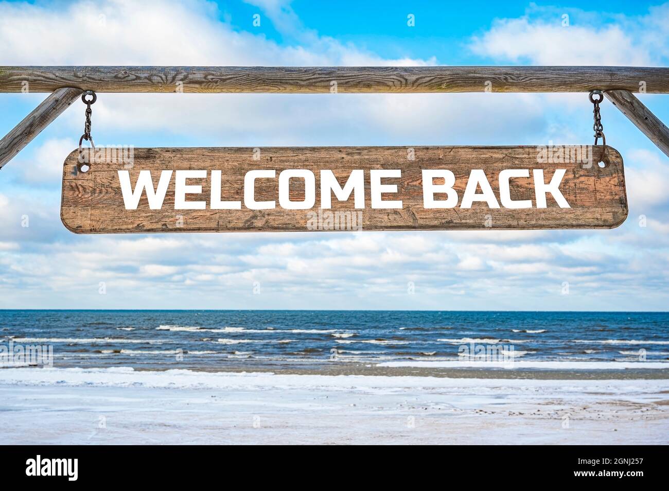 Willkommen zurück Holzschild gegen blauen Himmel und Meer mit Wellen Hintergrund. Stockfoto