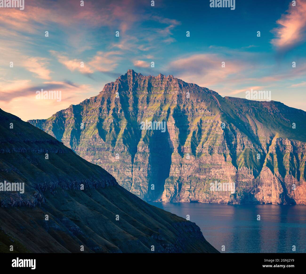 Fantastischer Sommersonnenaufgang auf den Färöern, Dänemark, Europa. Erste Sonnenlicht glühenden Bergrücken. Schönheit der Natur Konzept Hintergrund. Stockfoto