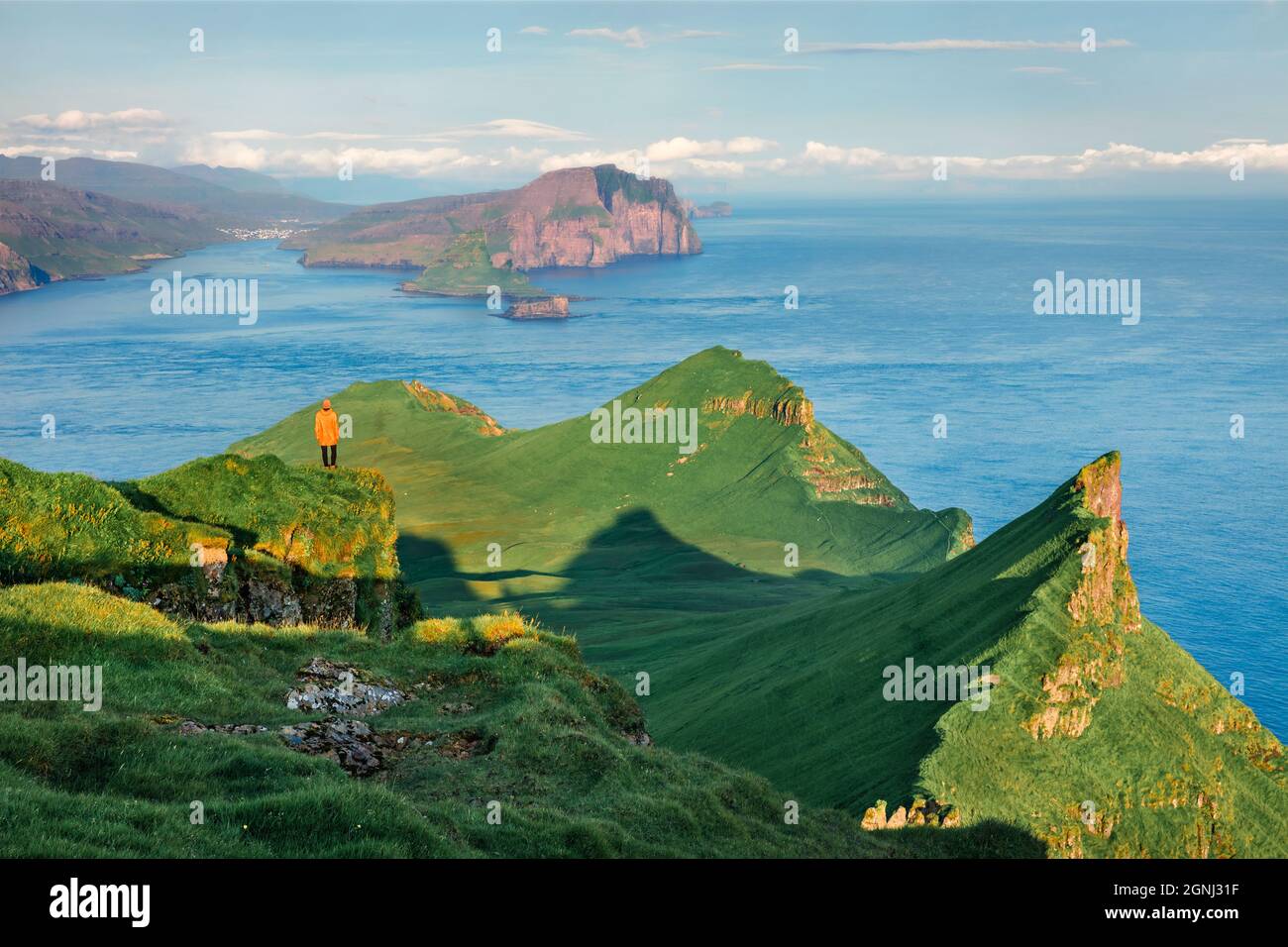 Einsamer Tourist, der die wunderschöne Berglandschaft, die Alaberg-Klippen, die Färöer-Inseln, das Königreich Dänemark, Europa bewundert. Sonniger Blick auf die Insel Mykines am Morgen Stockfoto