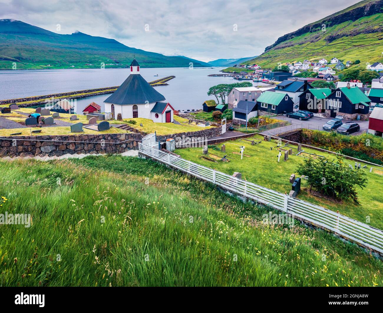 Düsterer Sommer Blick auf Haldarsvik Dorf mit Haldorsvikar Kirche. Grüne Morgenszene der Insel Streymoy, Färöer-Inseln, Königreich Dänemark, Europa. Stockfoto