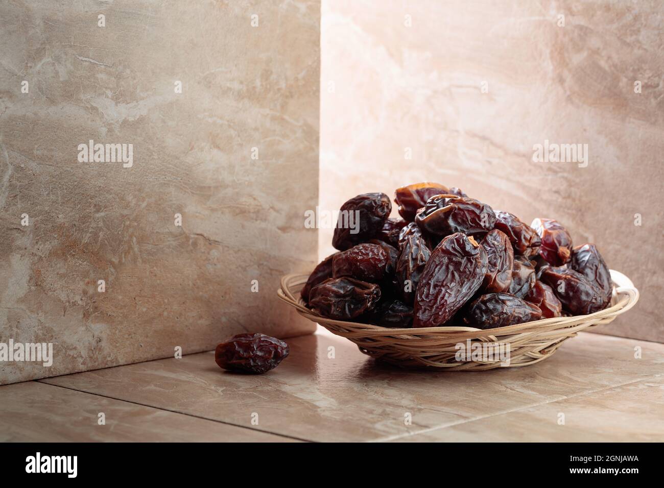 Frische Datteln Obst in einer Korbschale auf einem beigefarbenen Keramiktisch. Speicherplatz kopieren. Stockfoto