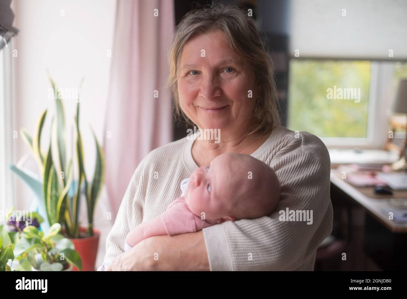Ältere Großmutter, die ein Neugeborenes in den Armen hält Stockfoto