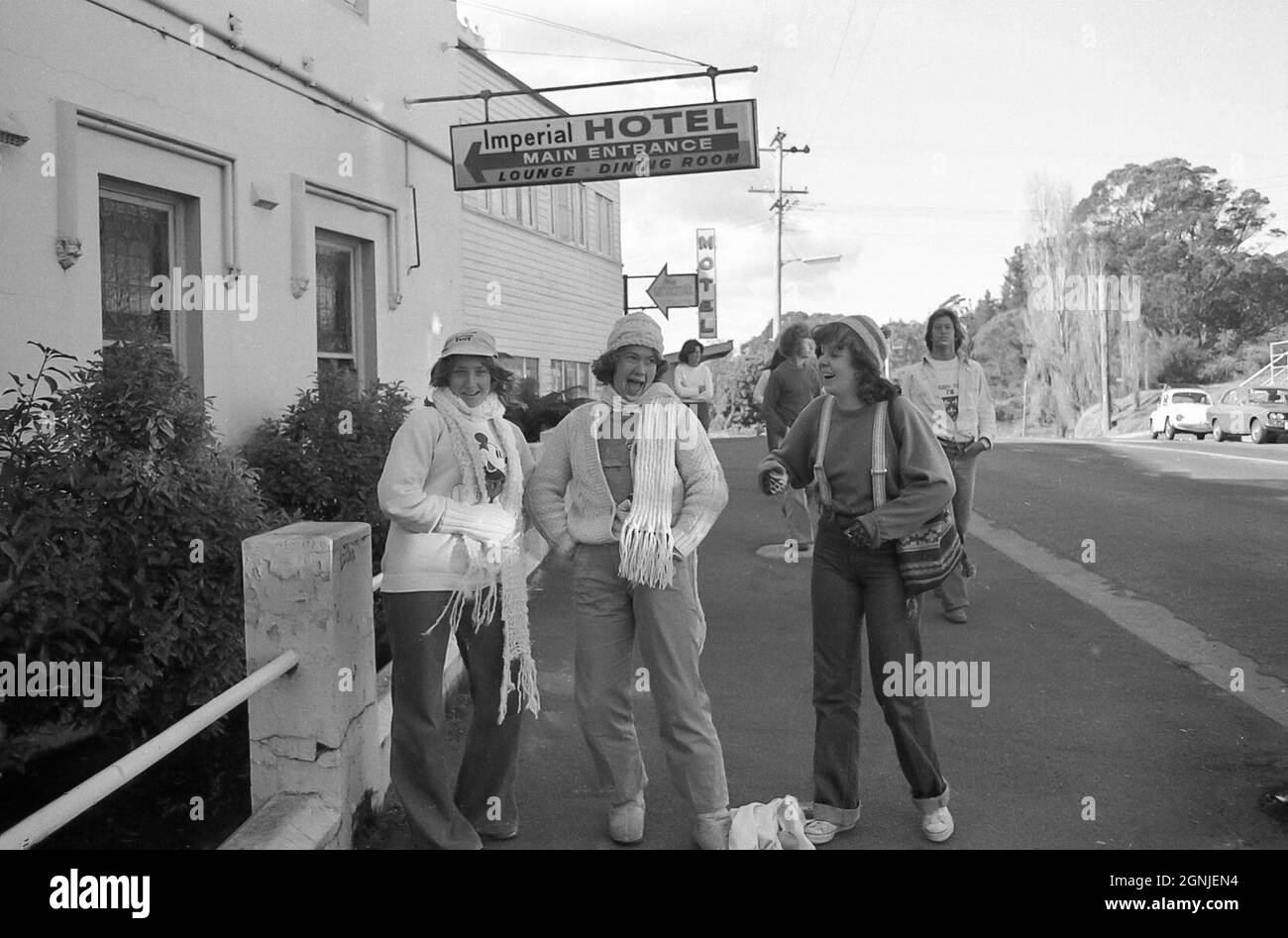 Für den Winter in Wollschals und Beanies gekleidet, stehen 12 Jugendliche (Mädchen/Frauen) der 1978. Klasse vor dem Imperial Hotel in Mount Victoria, New South Wales in den Blue Mountains, Australien, und lachen dort Stockfoto