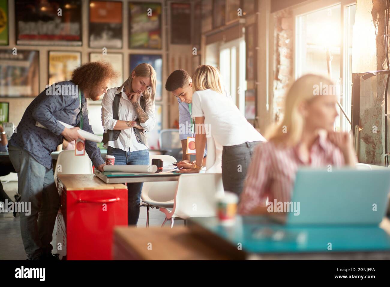 Selektiver Fokus auf eine Gruppe von jungen Erwachsenen, die sich um den Tisch versammelten und neues Design analysierten Stockfoto