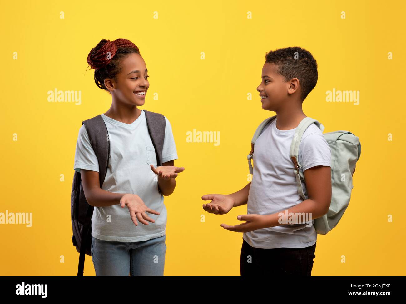 Glückliche afroamerikanische Schüler, die sich auf Gelb unterhalten Stockfoto
