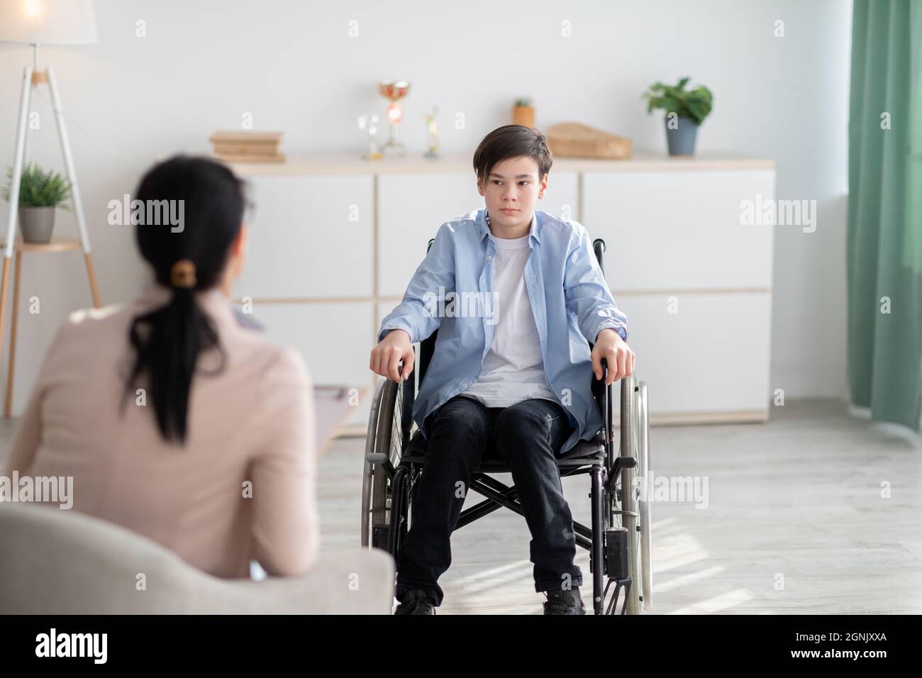 Psychologischer Hilfsdienst. Behinderter Teenager-Junge im Rollstuhl mit Psychotherapie-Sitzung mit Berater in der Klinik Stockfoto