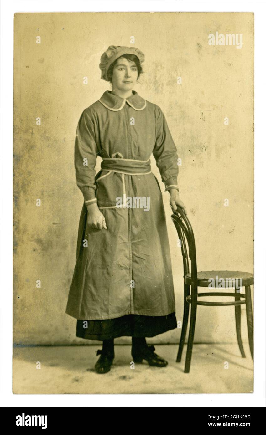 Originalpostkarte aus der Zeit des 1. Weltkriegs von einer hübschen Arbeiterin der Fabrik, mit Tunika und Mob-Mütze, möglicherweise Munitionsarbeiterin, um 1916, unbekannter Standort, Großbritannien Stockfoto