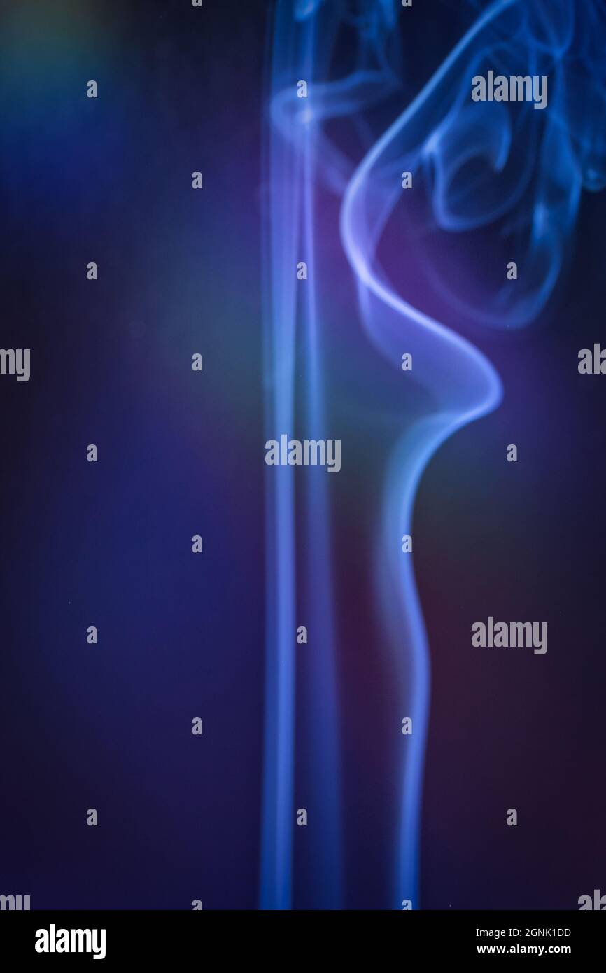 Eine vertikale Rauchaufnahme in farbiger Hintergrundbeleuchtung mit blauer Note Stockfoto