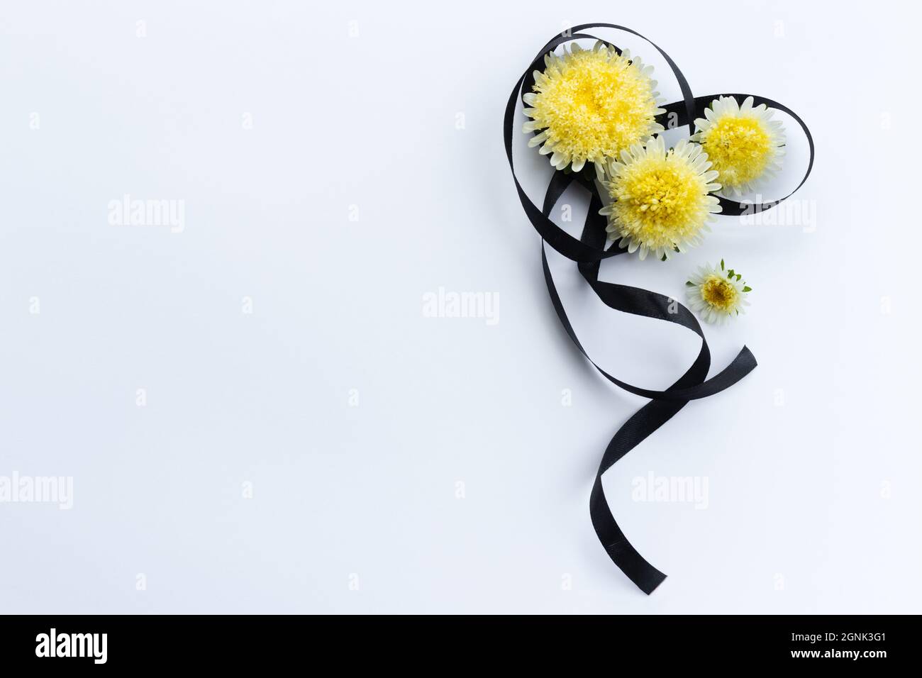 Dekoration aus schwarzem Trauerband mit gelben Blüten. Stockfoto