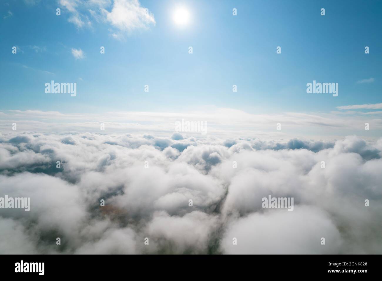 Cumulus Wolken, Lufthintergrund. Luftaufnahme mit Blick von oben auf weiße, flauschige Wolken, die sich sammeln. Zwischen den Wolken ist hier und da der Boden sichtbar Stockfoto