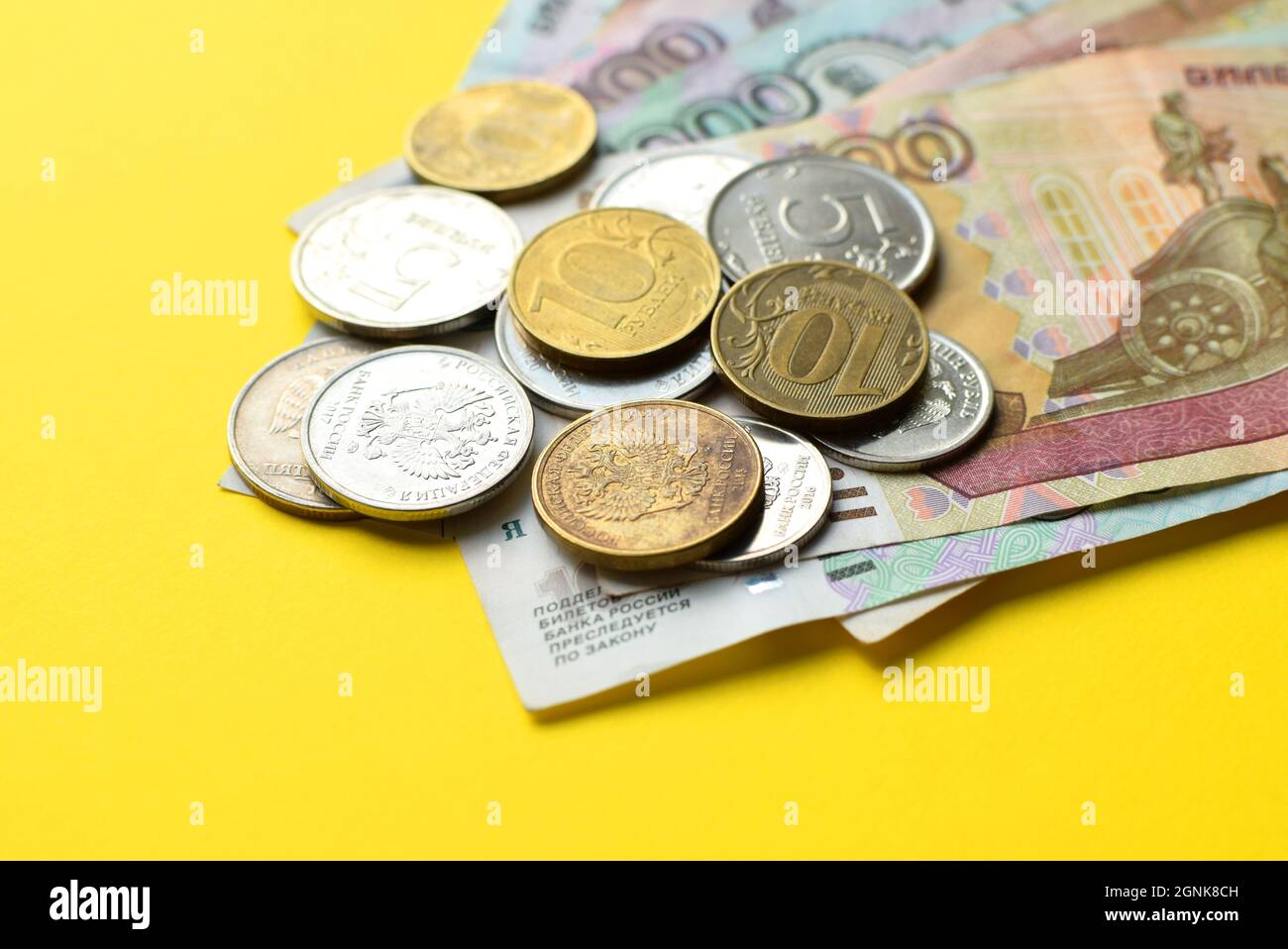 Russische Rubel auf gelbem Hintergrund. Banknoten und verschiedene Münzen. Stockfoto