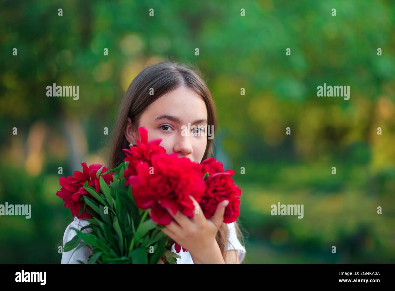 Schöne Teenager-Mädchen lächelt mit Pfingstrosen Blumen im Sommergarten Stockfoto