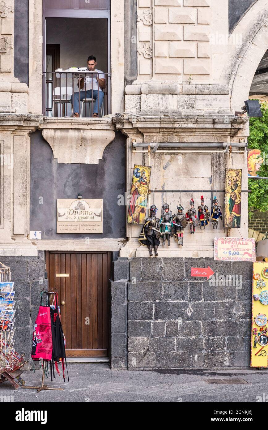 Stadtleben - ein Mann beim Frühstück am offenen Fenster einer Wohnung im ersten Stock auf der Piazza del Duomo im Zentrum von Catania, Sizilien, Italien Stockfoto
