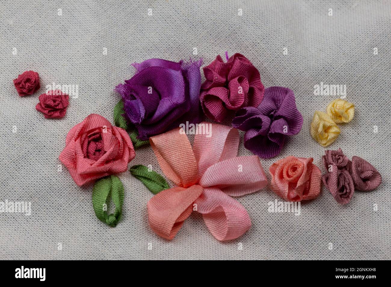 Stickerei Sampler Leinwand mit Beispielen von Seidenband Blumen in rosa, rot, lila und gelb Farben Stockfoto