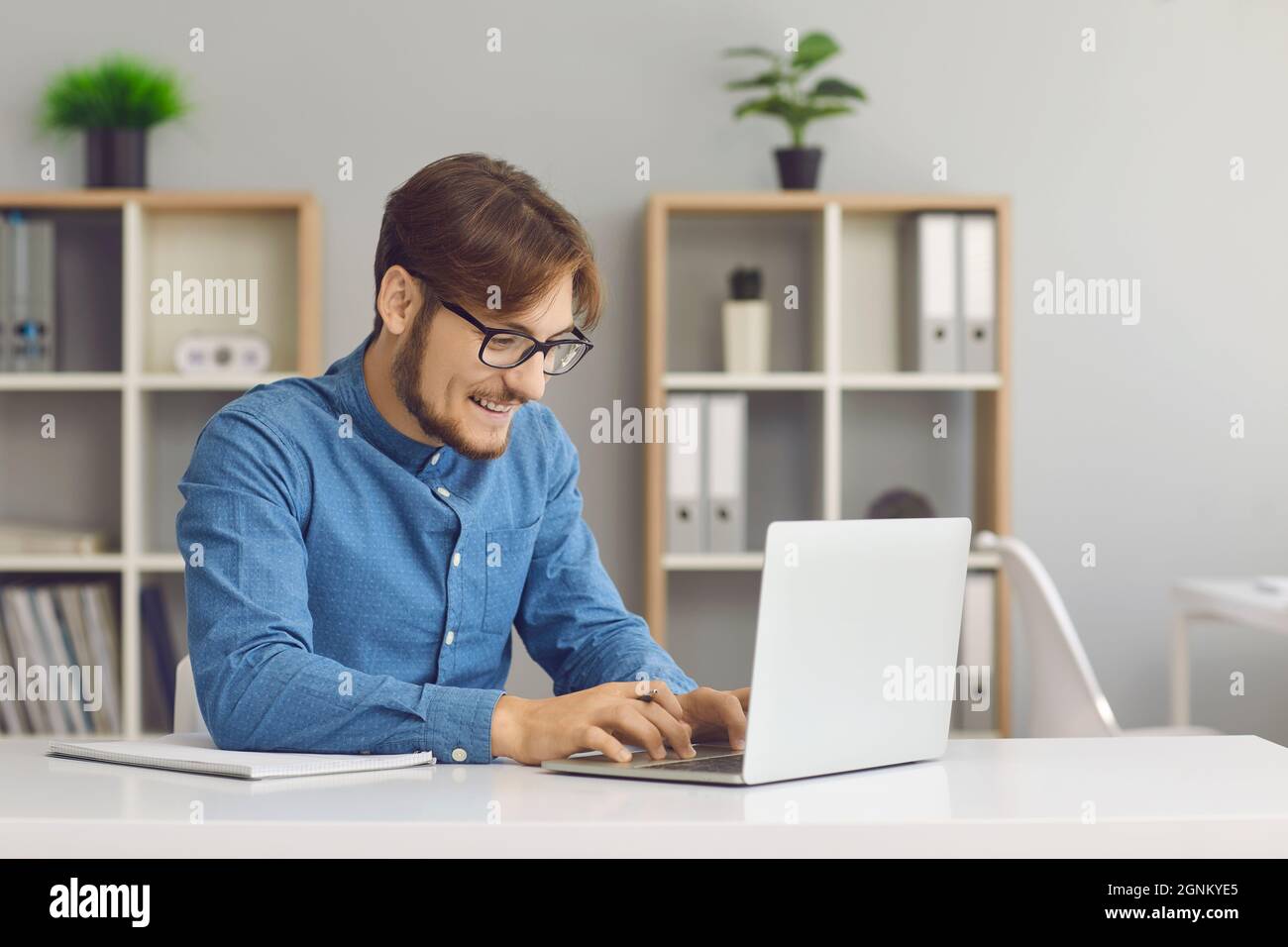 Junger Geschäftsmann, der mit einem Laptop arbeitet und elektronische Dokumente im Büro hat. Stockfoto