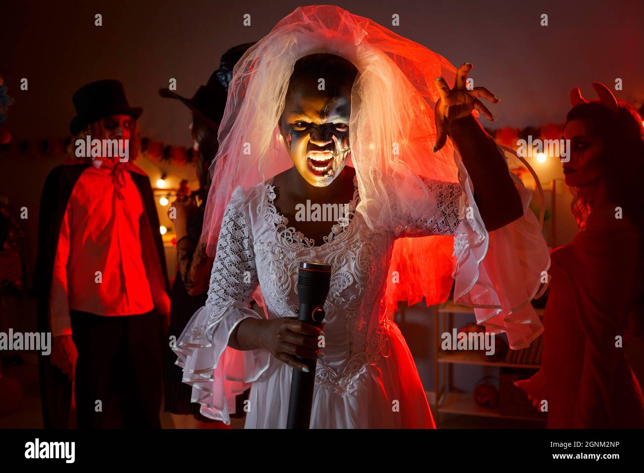 Frau als Leiche Braut für Halloween-Party mit Taschenlampe, die ihr Gesicht leuchtet gekleidet Stockfoto