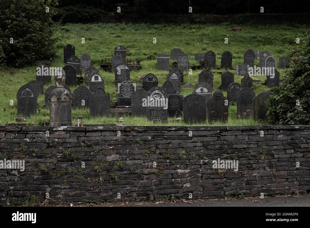 Historischer walisischer Friedhof mit verwitterten Grabsteinen und Trockenmauer Stockfoto