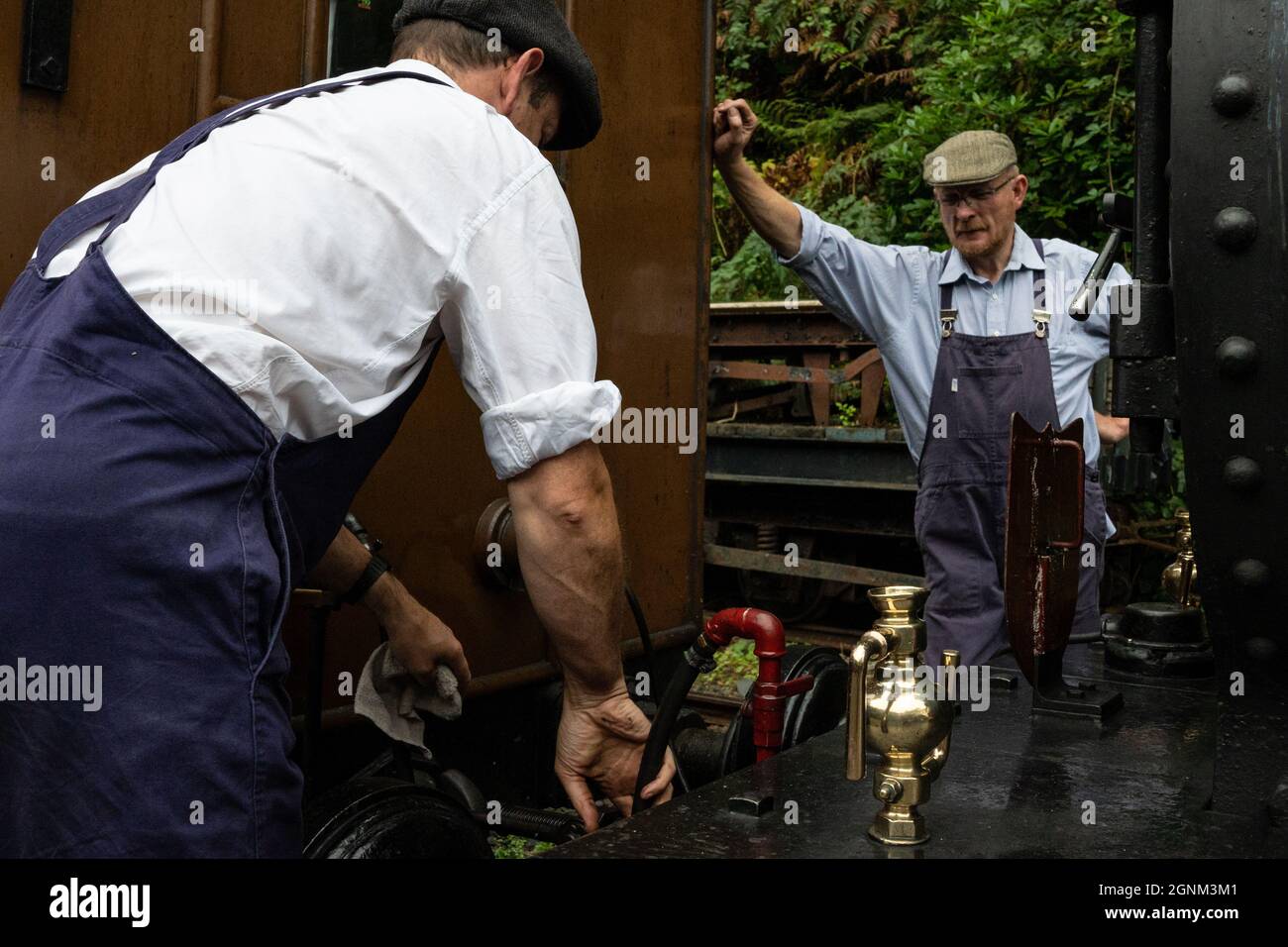Traditionelle Handwerker, die historische Dampfmaschinenanlagen in traditioneller Eisenbahnumgebung betreiben Stockfoto