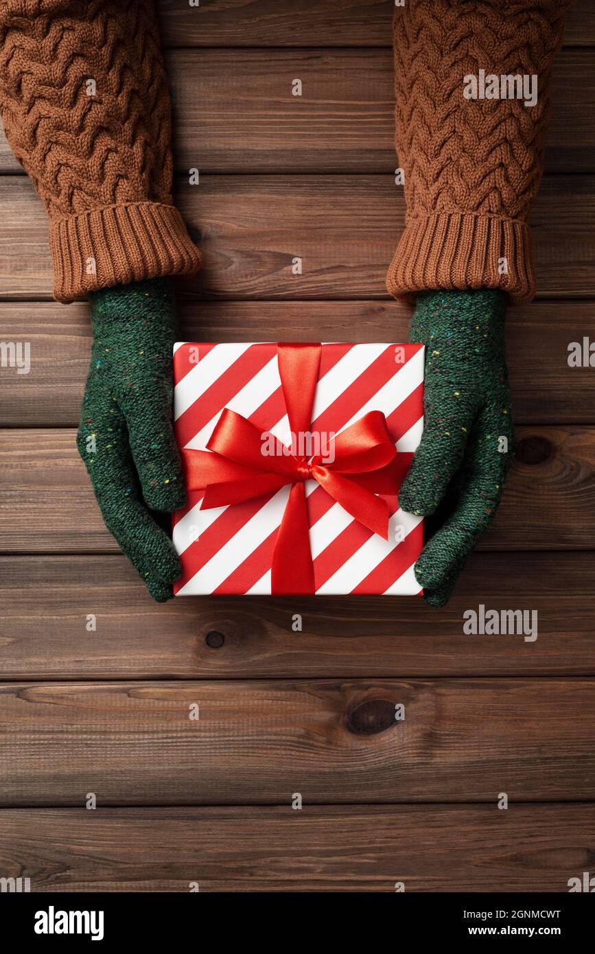 Weihnachts-Geschenk-Austausch-Tag. Eine Schachtel mit einem Weihnachtsgeschenk in den Händen von Frauen Stockfoto