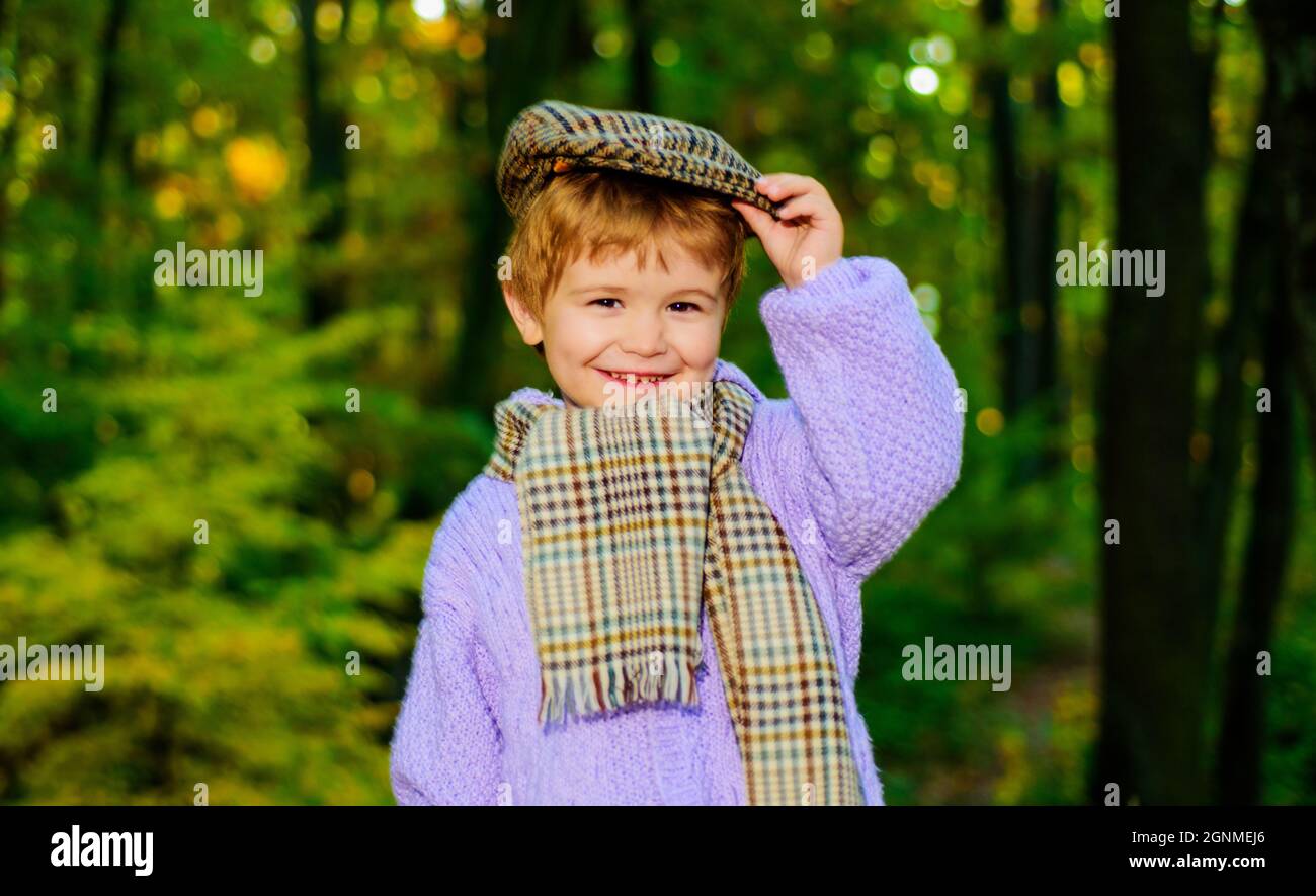 Lächelnder Junge in Pullover, Hut und Schal. Kleines Kind im Herbstpark. Niedliches Kind in warmer Kleidung. Stockfoto