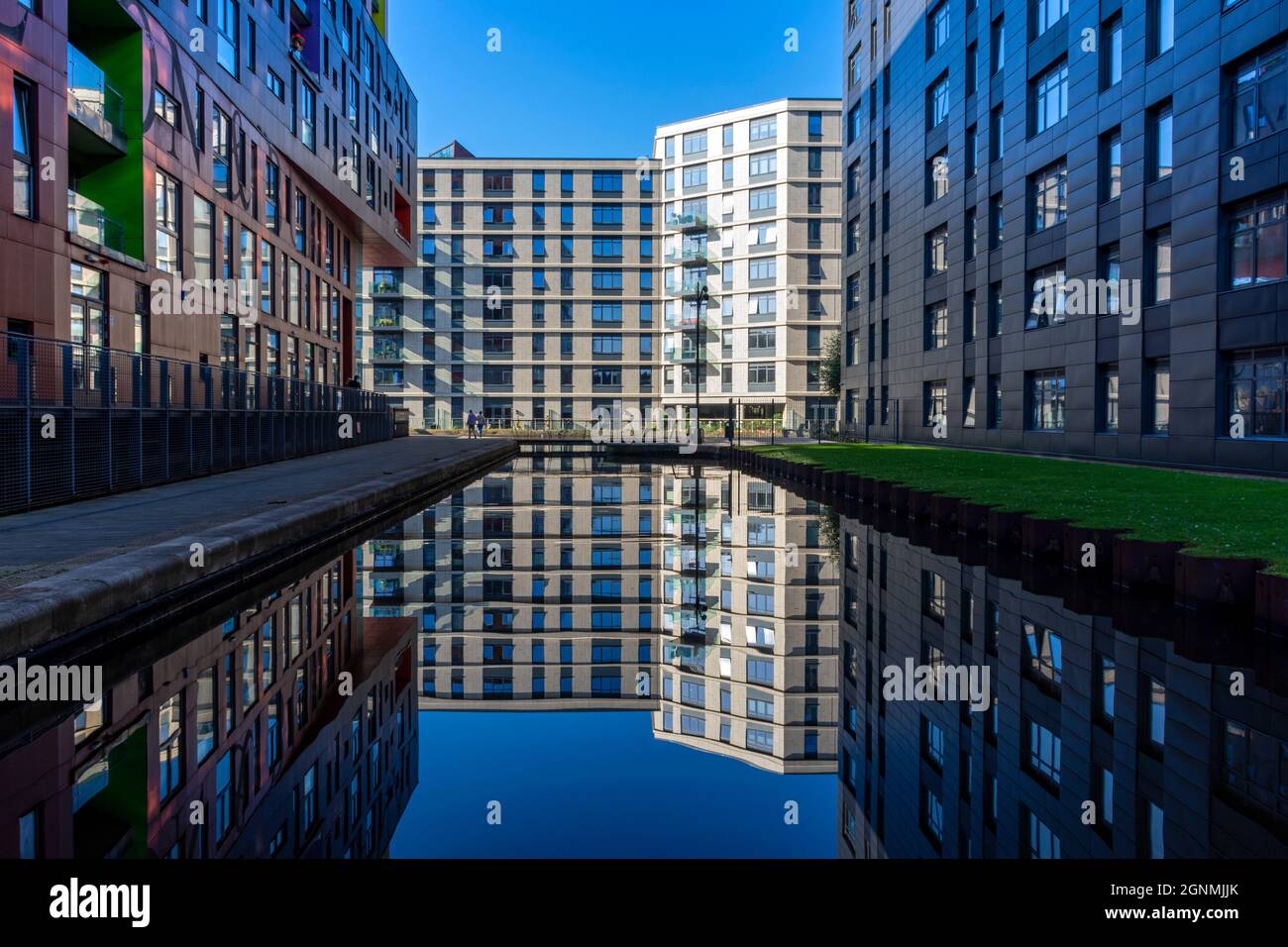 Die Wohnblocks The Chips, One Vesta Street und Lampwick spiegeln sich in der New Islington Marina, Ancoats, Manchester, England, Großbritannien Stockfoto