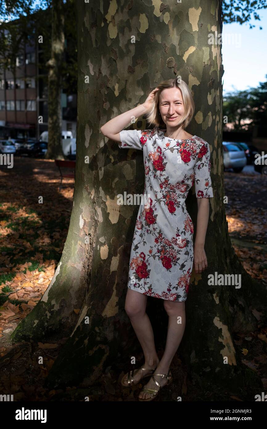 Frau, die in der Nähe des Platanenbaums in der Stadt steht. Stockfoto