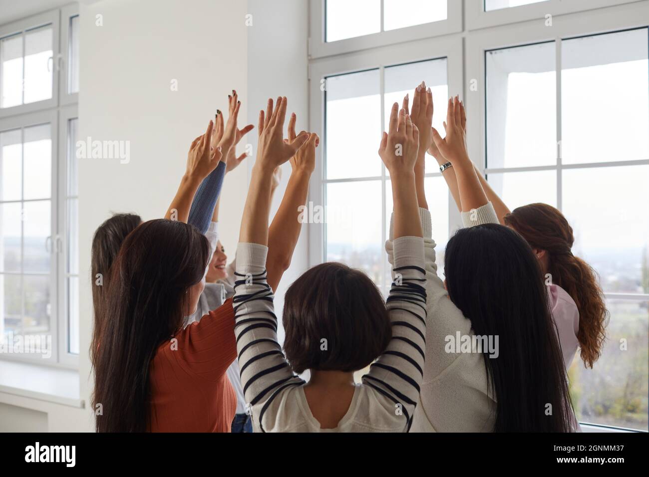 Zugeschnittenes Bild einer Gruppe glücklicher Frauen, die im Kreis mit erhobenen Armen zusammenstehen. Stockfoto