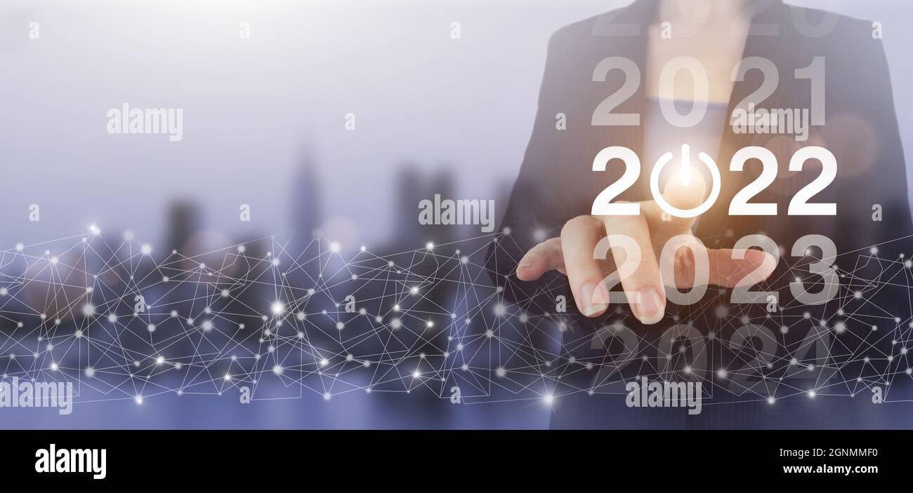 Willkommen im Jahr 2022. Konzept der Visitenkarte für das neue Jahr. Hand berühren digitalen Bildschirm Hologramm 2022 Zeichen auf Stadt Licht verschwommen Hintergrund. Geschäftsneujahr ca. Stockfoto