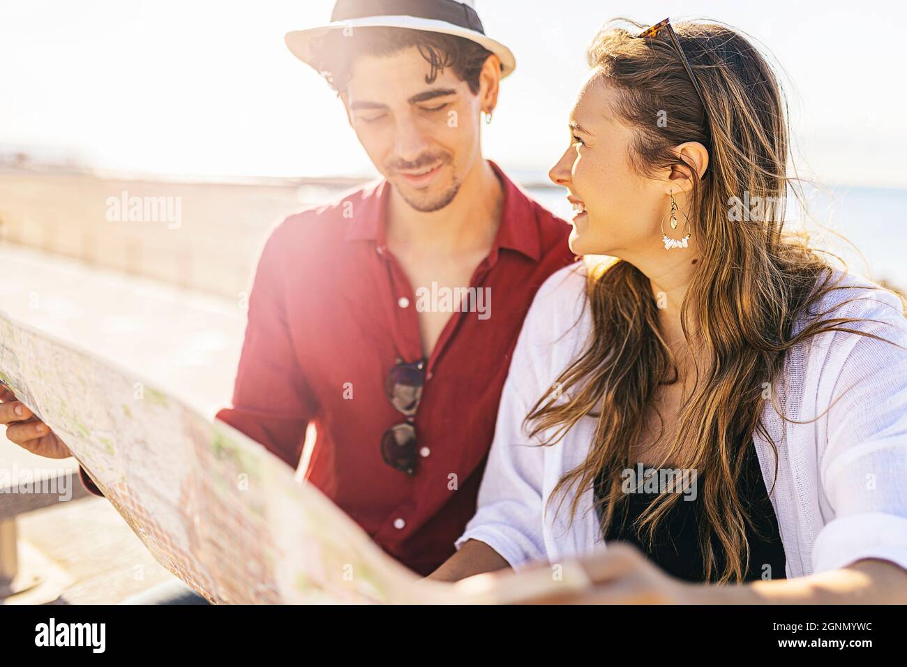 Junge Hipster, ein paar Reisende, die im Urlaub am Strand eine Karte lesen Stockfoto