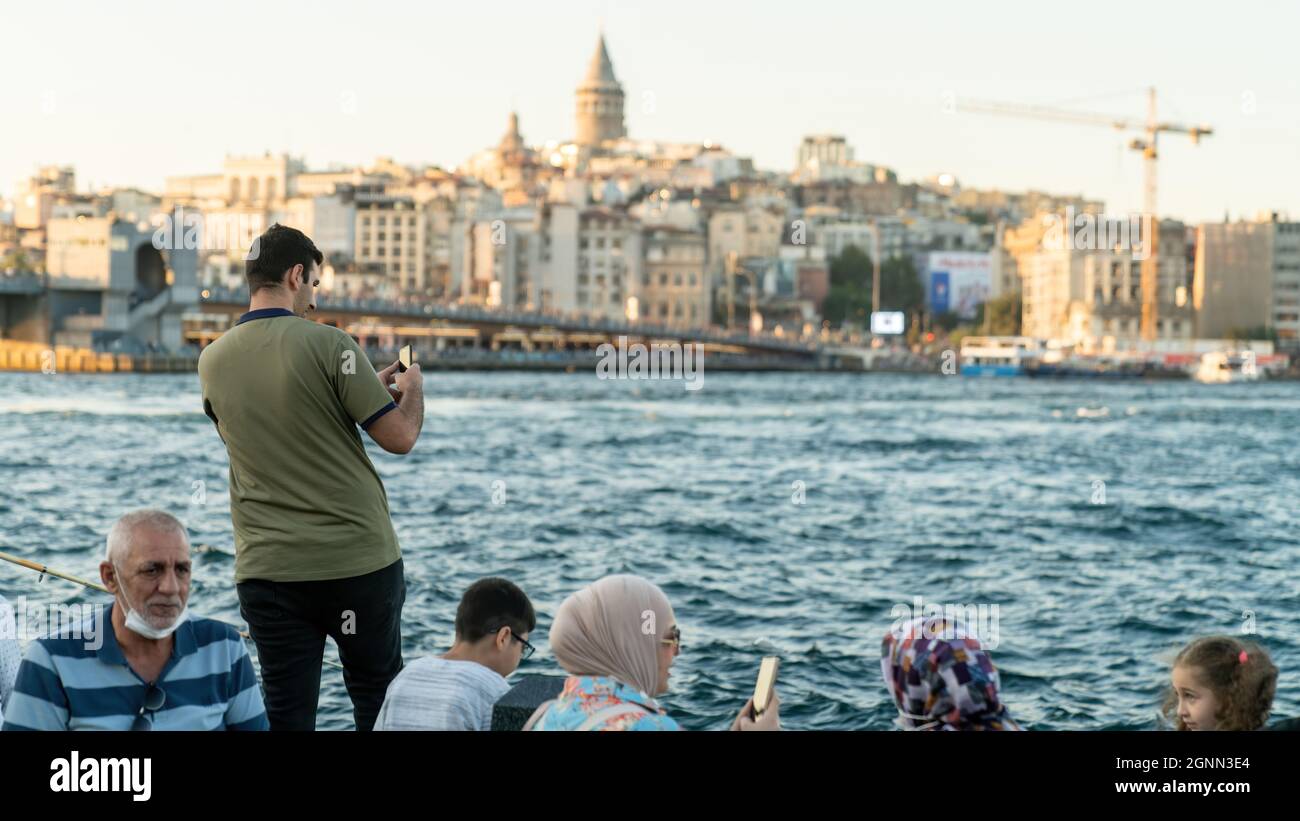Istanbul, Türkei - 2021. September: Touristen und Einheimische am Eminonu-Ufer. Touristen fotografieren die Stadt Istanbul. Galata Turm bietet eine Stockfoto