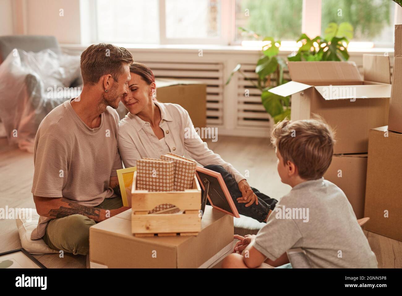 Porträt einer glücklichen Familie mit Sohn Auspacken Boxen in gemütlichen Raum, während in ein neues Zuhause, kopieren Raum Stockfoto