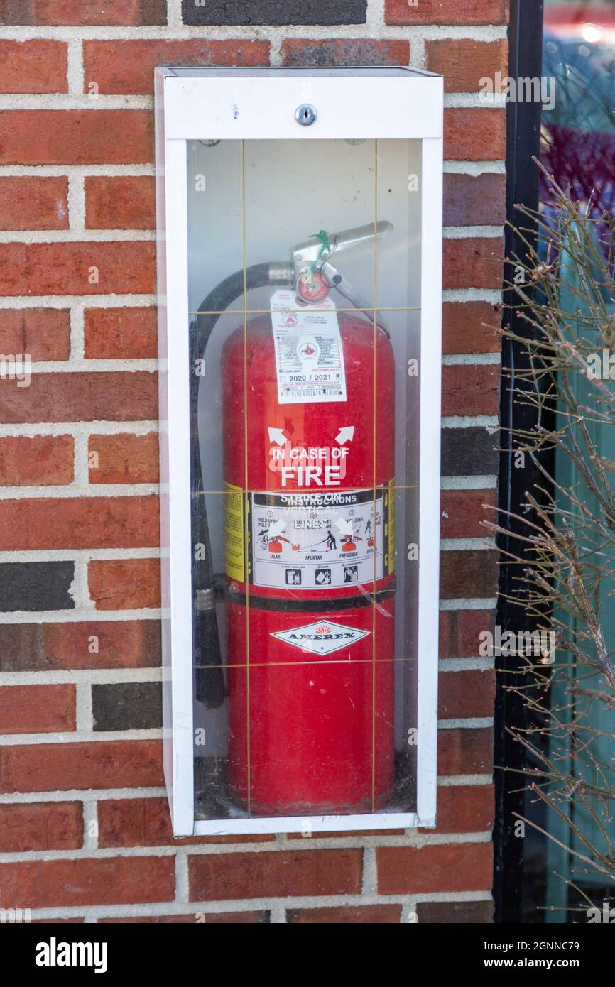 Ein roter Amerex-Feuerlöscher in einem Schrank an einer Ziegelwand. Stockfoto