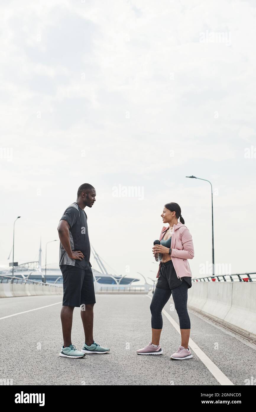 Afrikanisches sportives Paar, das während ihres Treffens im Freien miteinander sprach, diskutierte über Sportübungen Stockfoto