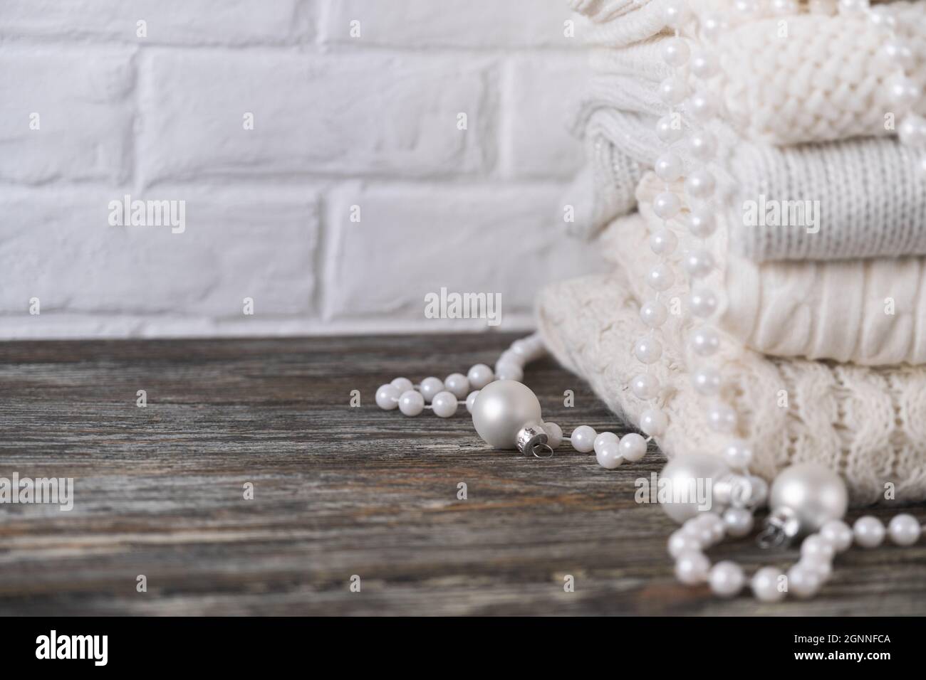 Stapel von weißen, kuscheligen Strickpullover auf Holztisch Stockfoto