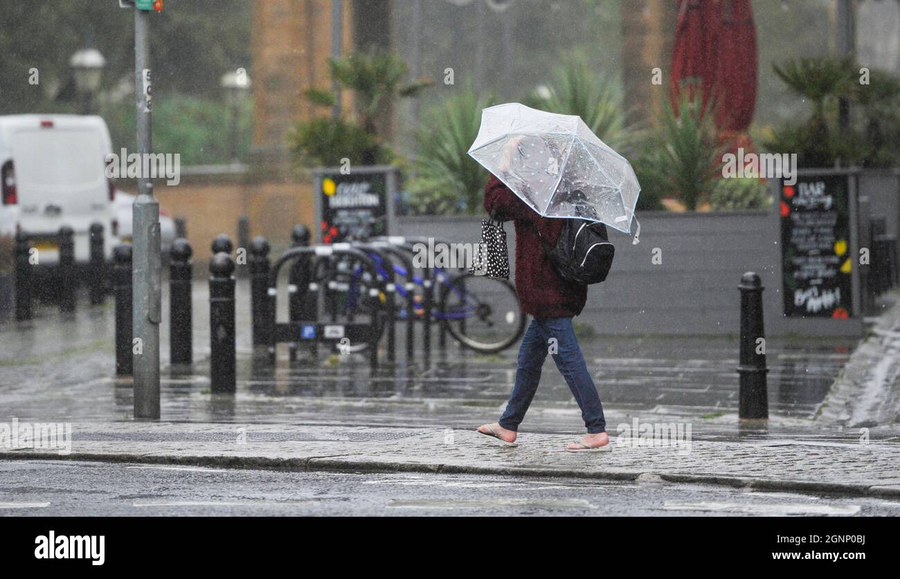 Brighton UK 27. September 2021 - ein Regenschirm und Flip Flops für diesen Wanderer in Brighton, während heute nasses und windiges Wetter über Großbritannien fegt : Credit Simon Dack / Alamy Live News Stockfoto